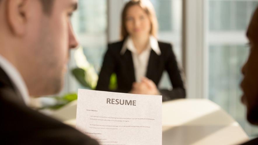 A job applicant presenting a resume during an interview with two interviewers.